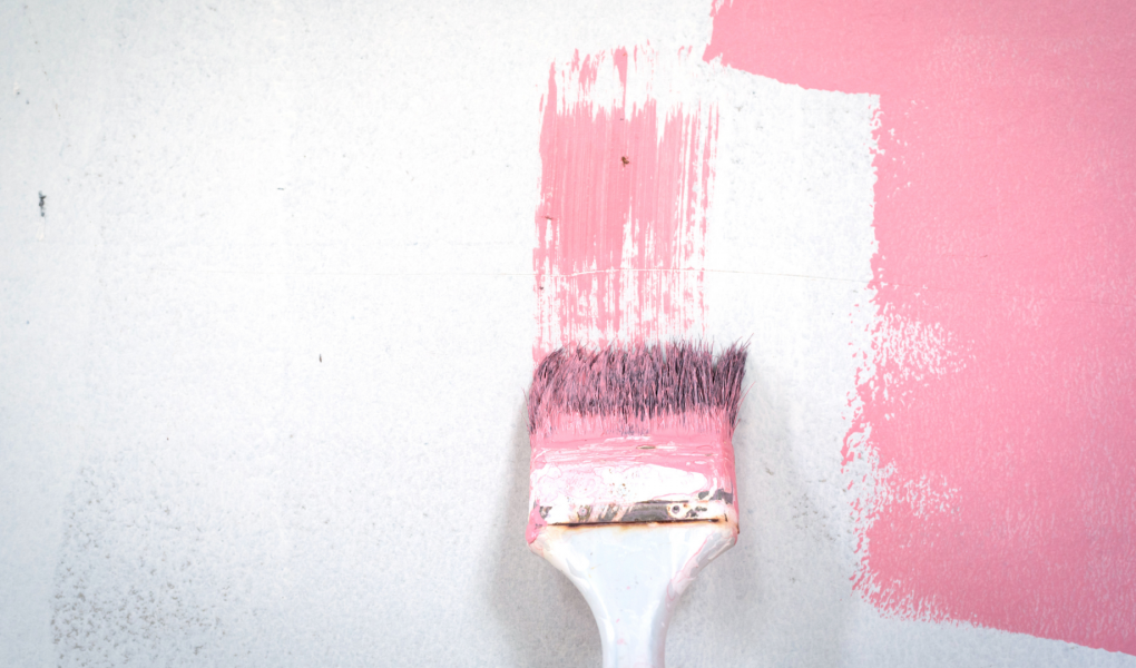 paintbrush painting pink paint on white wall