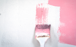 paintbrush painting pink paint on white wall