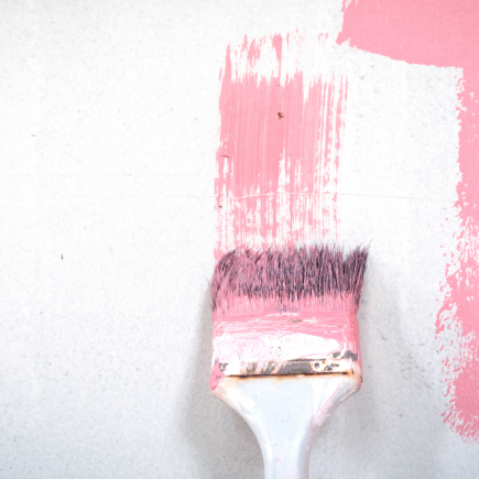 paintbrush painting pink paint on white wall